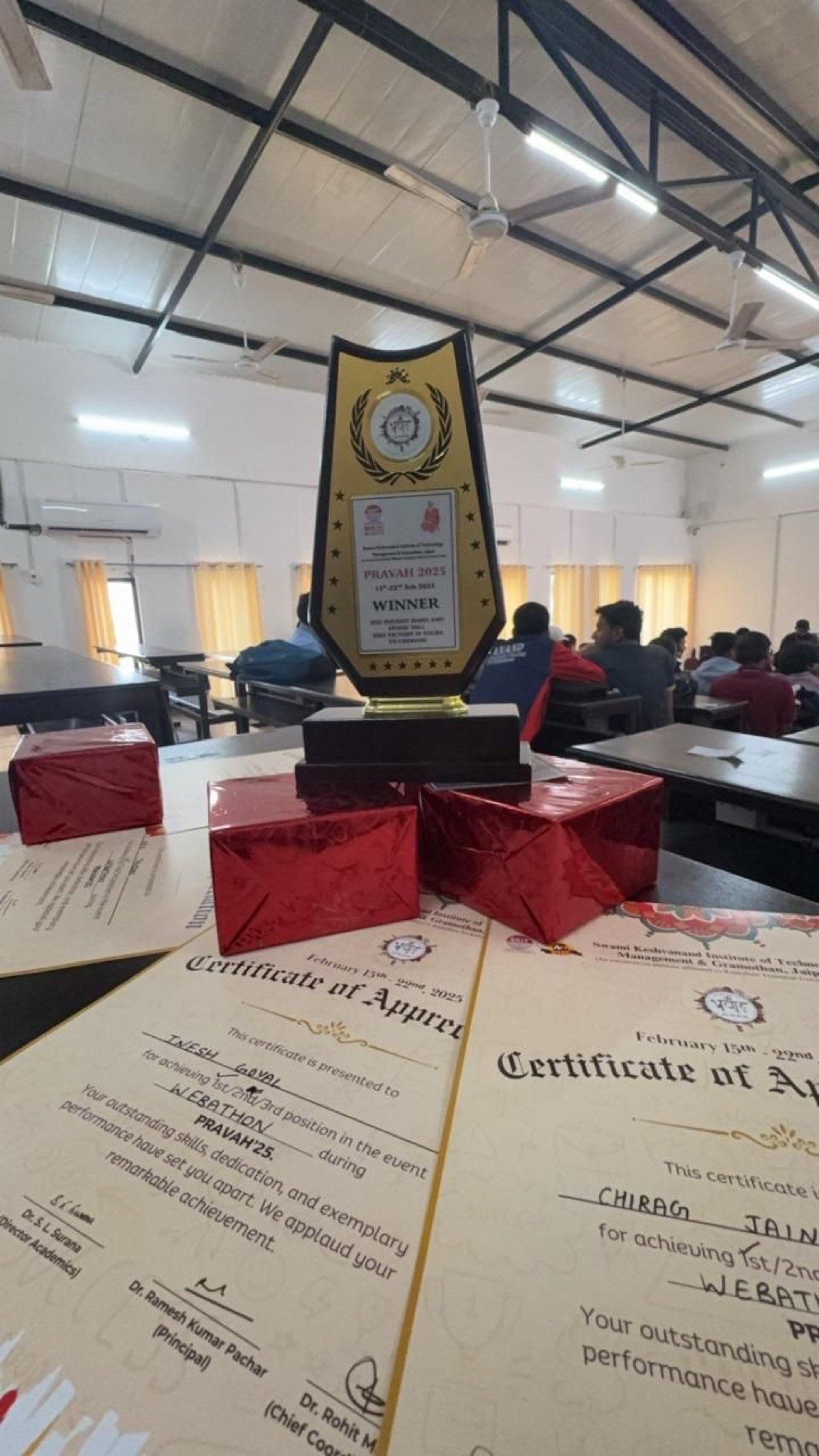 The PRAVAH 2025 winner’s trophy from SKIT Jaipur, standing on a desk beside the Webathon certificates
